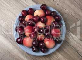 Sweet cherries and ripe juicy nectarines in a dish, on wooden ba