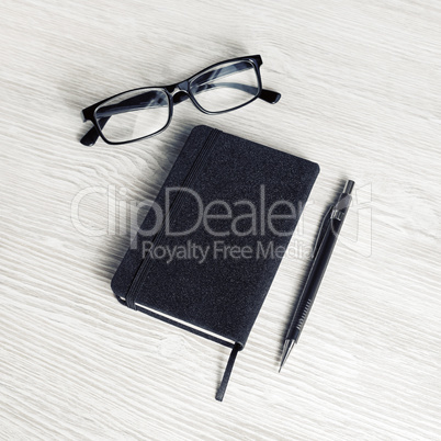 Black notebook, glasses, pencil