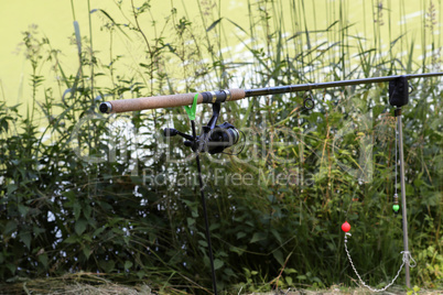 Angler fishing rod stands on a lake