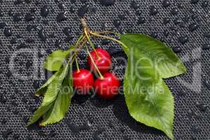 Red cherries with leaves lie on a table