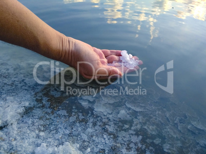 A piece of salt on the woman hand. Salt Lake. Natural salt. Salt production.