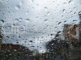 City street seen through rain drops on the car windshield. Bad Autumn weather in Rainy day. Windshield window of car with raindrops on glass windscreen.