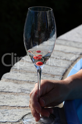 Glass with white wine and red berries in the hands of a woman