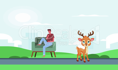 man sitting in a park looking at deer