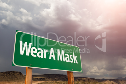 Wear A Mask Green Road Sign Against Ominous Stormy Cloudy Sky