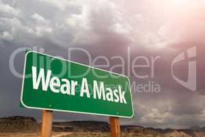 Wear A Mask Green Road Sign Against Ominous Stormy Cloudy Sky