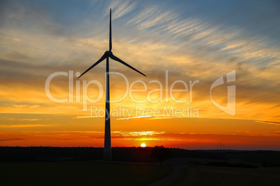 Sunny sunset with beautiful clouds and windmill silhouette