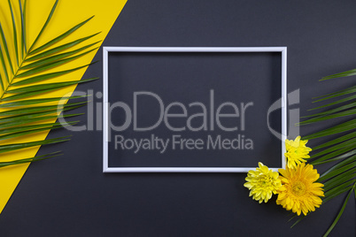 Frame of tropical palm leaves with flowers on black and yellow b