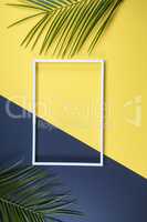 Summer composition with photo frame and green leaves on yellow b