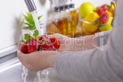 Woman washing strawberries in the kitchen