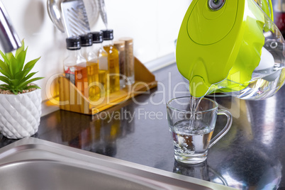 Pouring filtered water into glass from jug in the kitchen