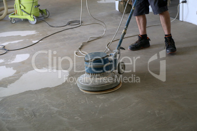 Worker grinding the floor using a single disc machine