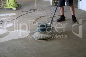 Worker grinding the floor using a single disc machine