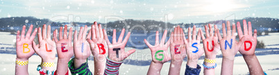 Kids Hands Holding Word Bleibt Gesund Means Stay Healthy, Snowy Winter Background