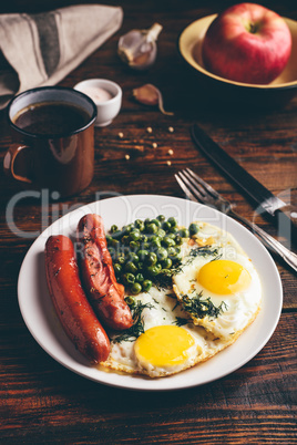 Breakfast with fried eggs, sausages and green peas