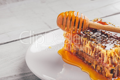 Honeycomb on plate with honey dipper