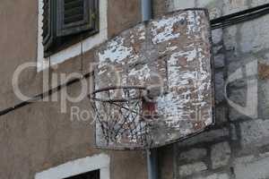 Old basketball ring is attached to the wall of the house