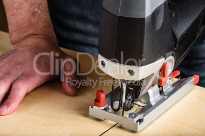 Man with electric jig saw cutting wood