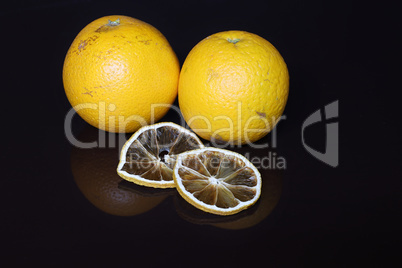 Fresh oranges and dried slices on a black background