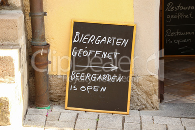 Plaque on the street. Text in German and English: Beergarden is open.