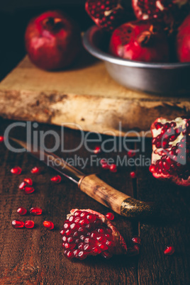 Pomegranate fruits with knife on wooden table