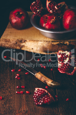 Pomegranate fruits with knife on wooden table