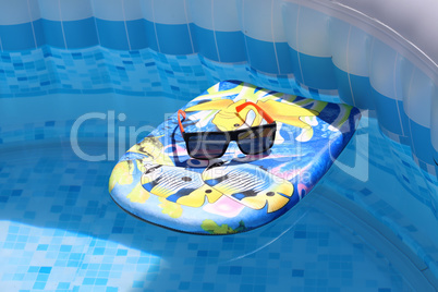 Swimming board with sunglasses in the pool