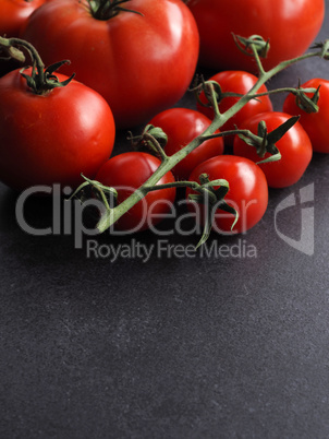 Different organic tomato varieties on a dark stone kitchen table