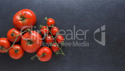 Different organic tomato varieties on a dark stone kitchen table