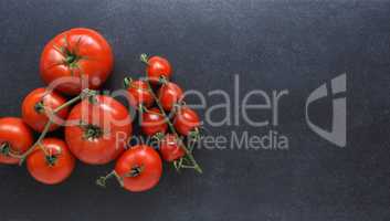 Different organic tomato varieties on a dark stone kitchen table