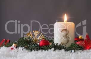 Candle of the third Advent burns, fir branches and Christmas tre