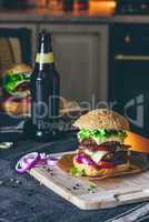 Prepared Cheeseburger on Cutting Board with  Bottle of Beer on T