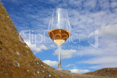 Glas mit Rosé Wein auf einem Stein