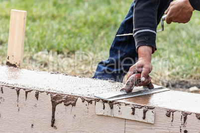 Construction Worker Using Wood Trowel On Wet Cement Forming Copi