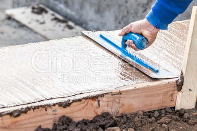 Construction Worker Using Trowel On Wet Cement Forming Coping Ar