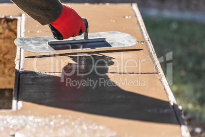 Construction Worker Using Trowel On Wet Cement Forming Coping Ar