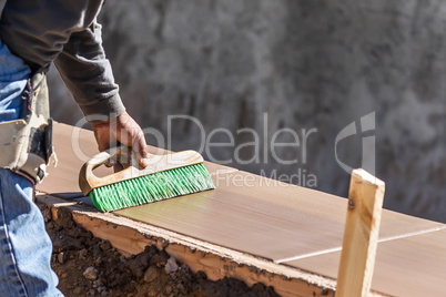 Construction Worker Using Brush On Wet Cement Forming Coping Aro