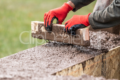 Construction Worker Leveling Wet Cement Into Wood Framing