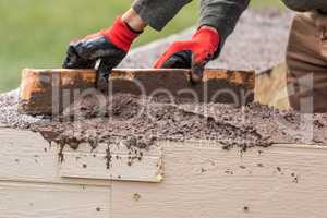 Construction Worker Leveling Wet Cement Into Wood Framing