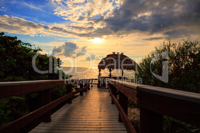 Tiki hut Boardwalk leads down to the white sand of Barefoot Beac