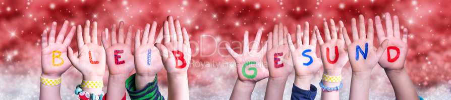 Children Hands Bleib Gesund Means Stay Healthy, Red Christmas Background