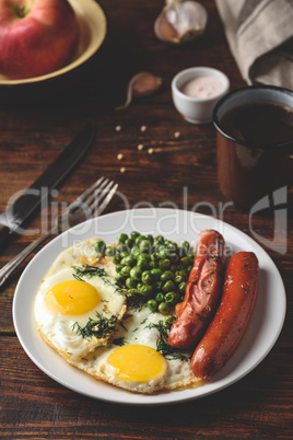 Breakfast with fried eggs, sausages and green peas