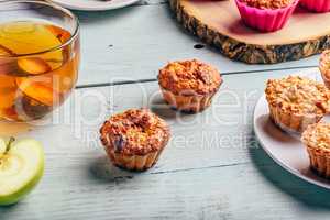 Cooked muffins with apple and cup of tea.