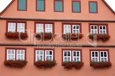 Facade of a house with geraniums on the windows