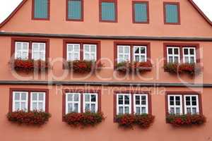 Facade of a house with geraniums on the windows