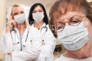 Senior Adult Female Looking Down as Doctors stand Behind All Wea