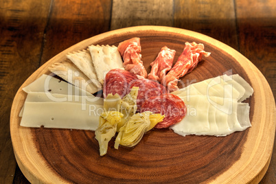 Charcuterie board on rustic wood with candles behind a spread of