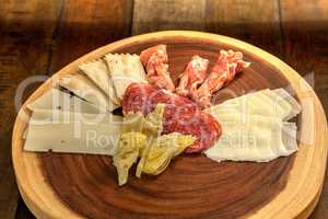 Charcuterie board on rustic wood with candles behind a spread of