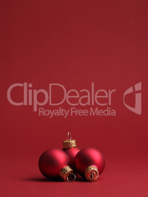 Three red vintage Christmas baubles on a red background