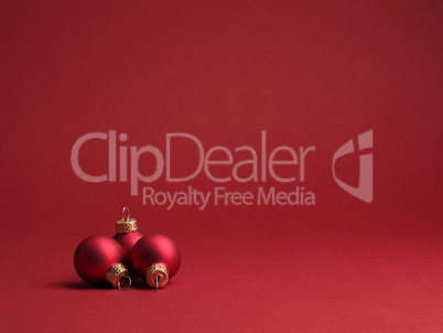 Three red vintage Christmas baubles on a red background